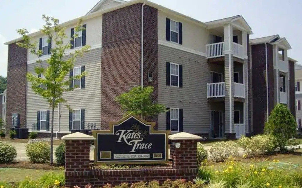 A brick building with a sign that says Kates Trace in front of it.